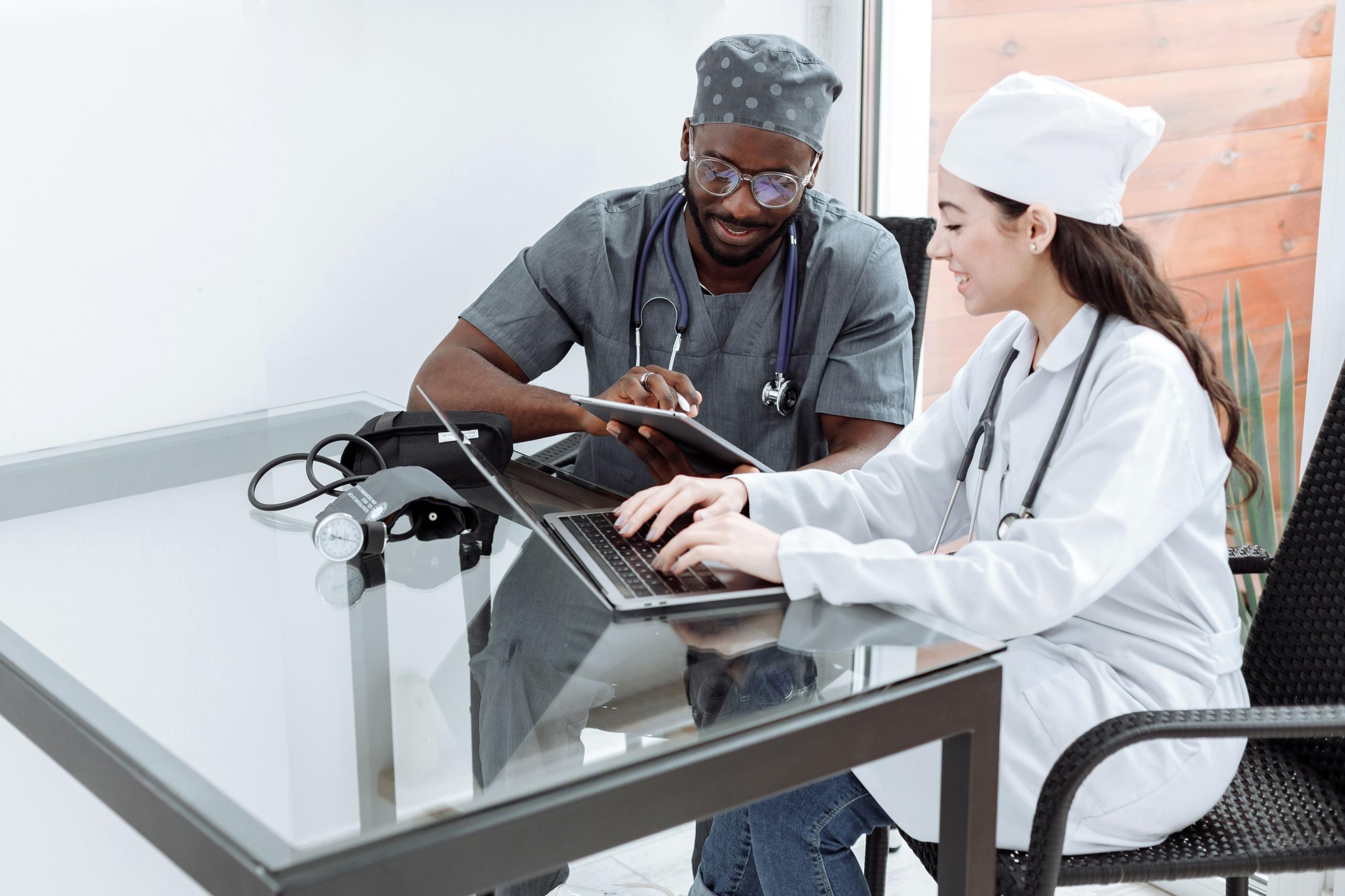 Two clinicians collaborating with a tablet and laptop in a modern clinical setting