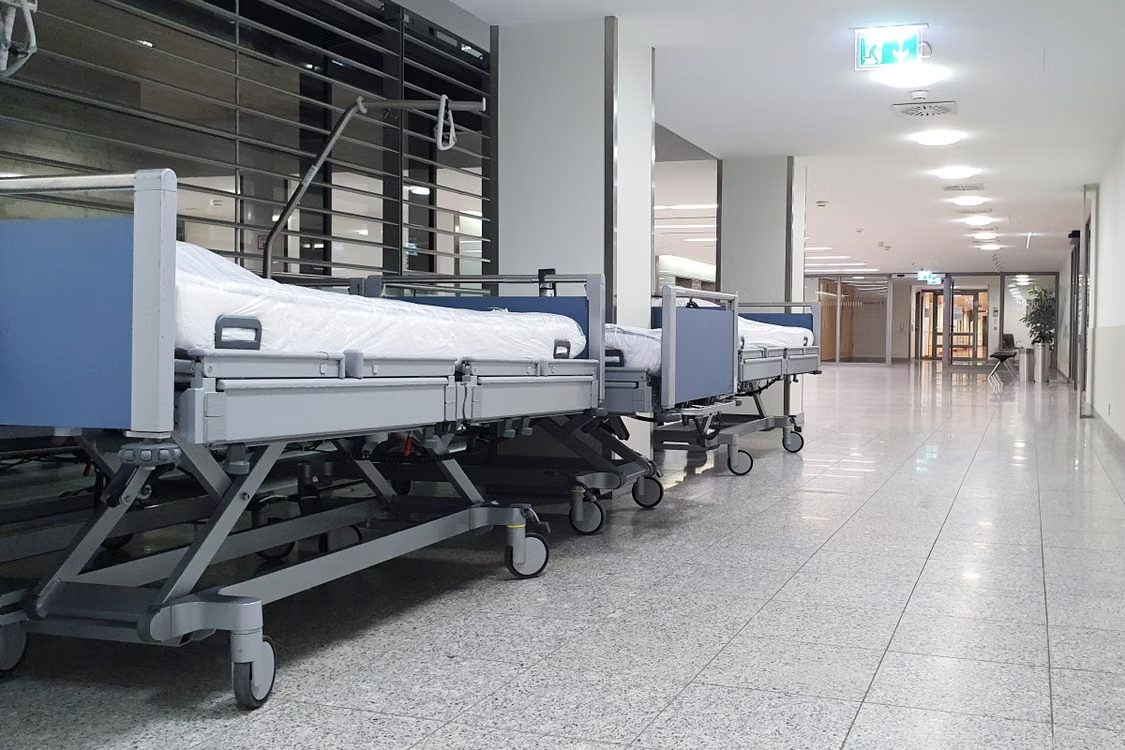 Empty gurneys lined along a bright hospital corridor